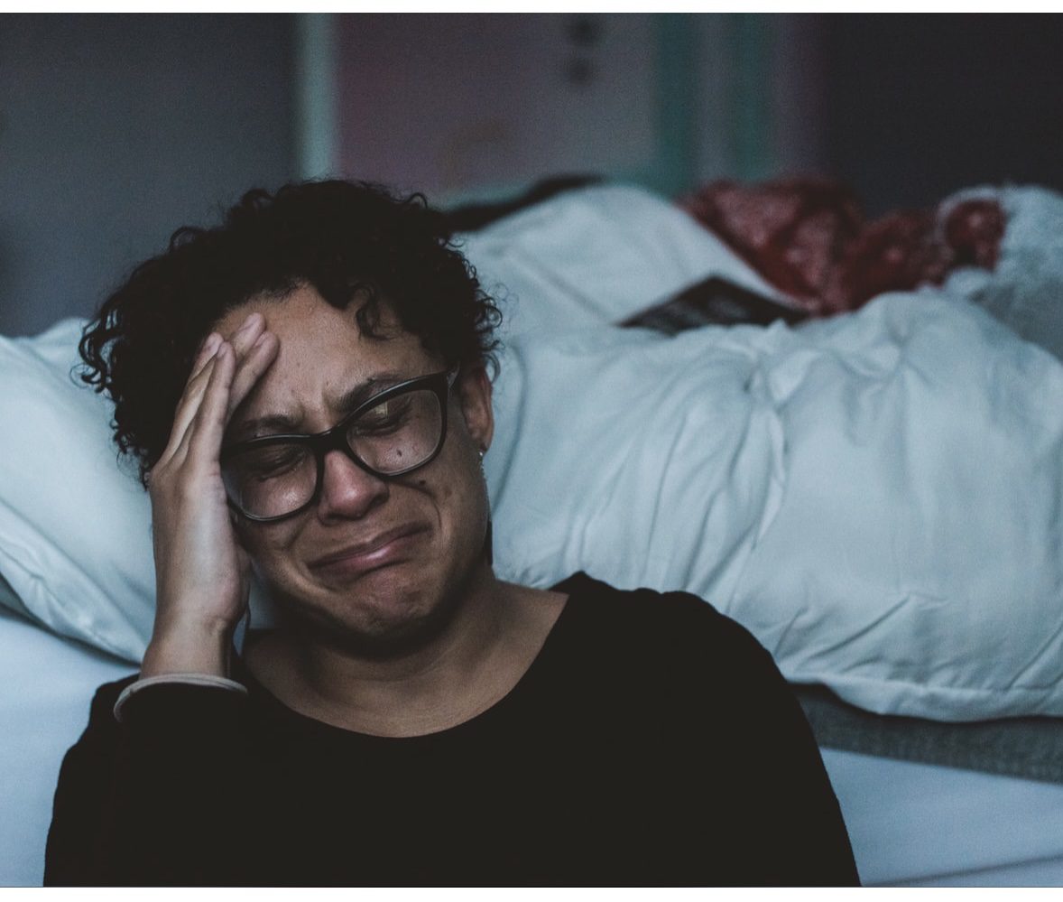 A woman with glasses sitting on the bed