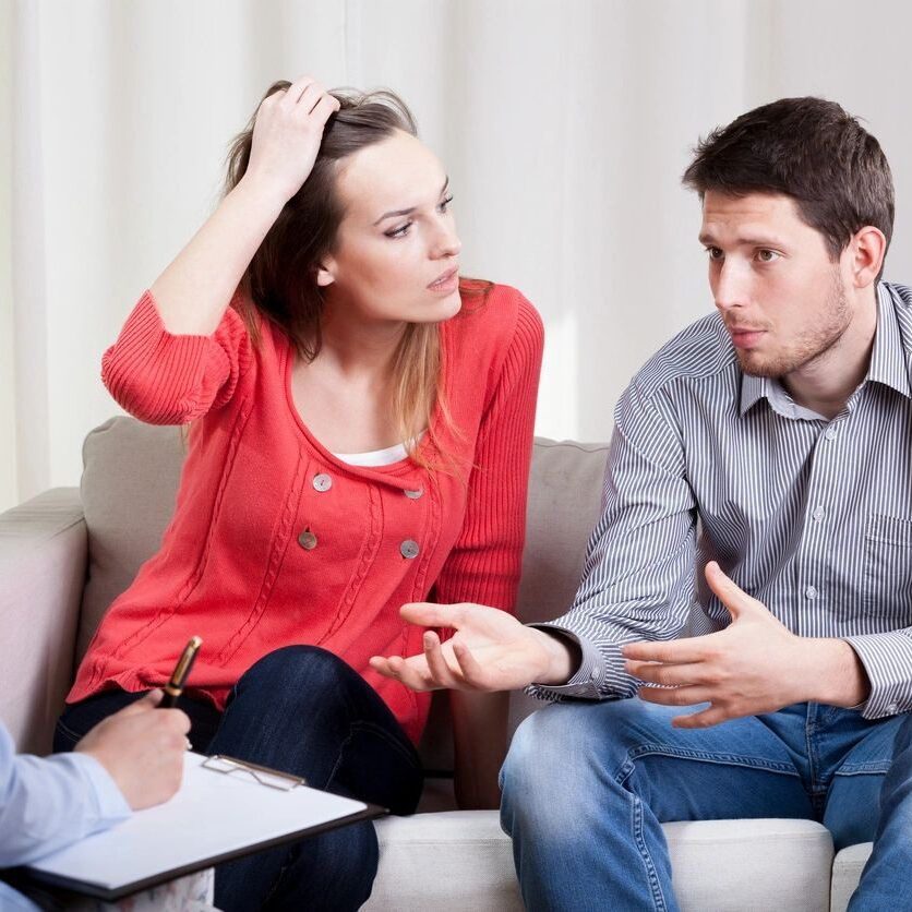 A woman sitting on the couch with two men.