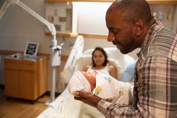 Father holding newborn baby at hospital