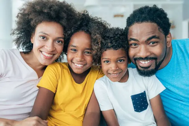 Smiling family of four, representing family mental health support, counseling, and wellness services.