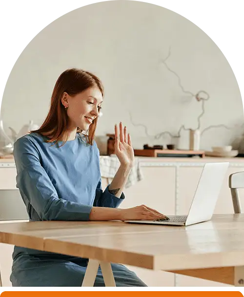 Smiling woman waving during an online therapy session, representing telehealth mental health services.