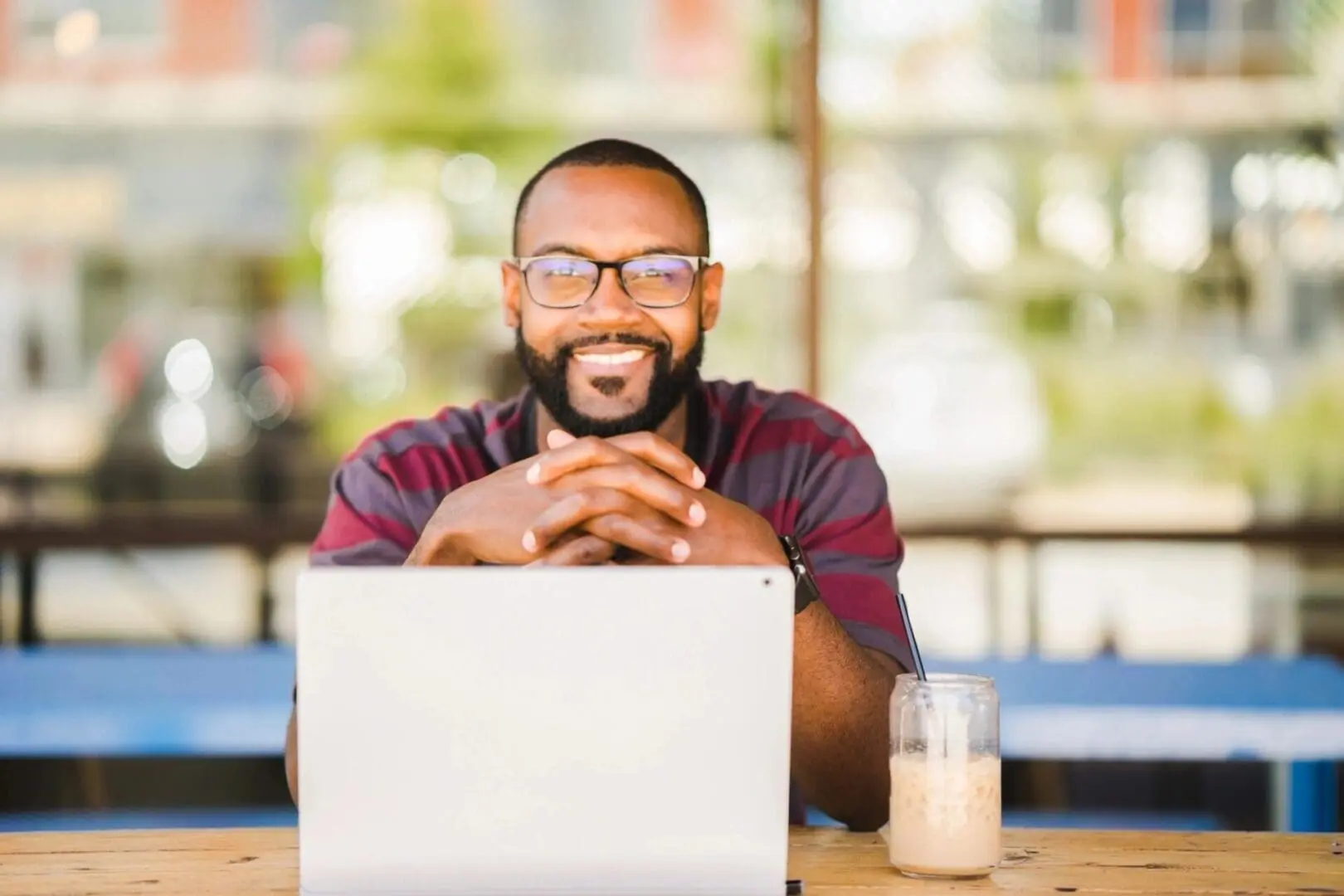 Man smiling at laptop with coffee.